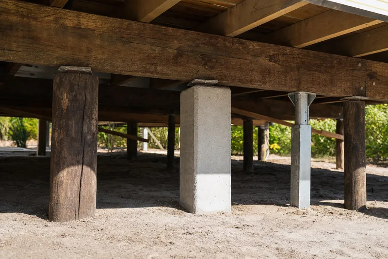 Three stump types side by side under a timber floor — weathered hardwood, precast concrete and galvanised steel, illustrative example