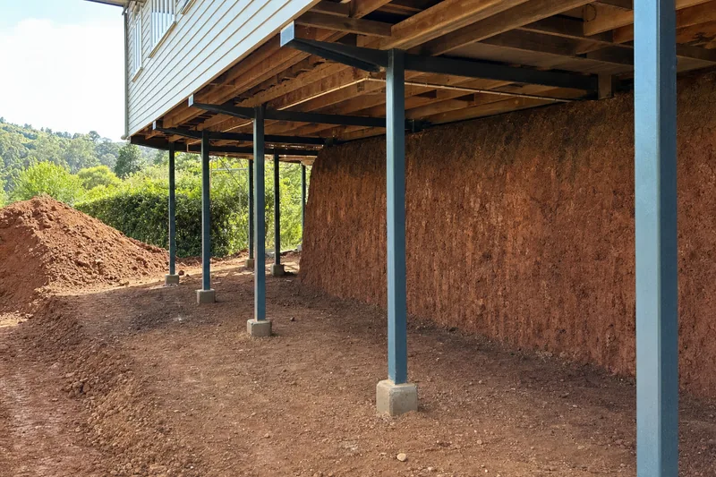 Dig-out beneath a raised Queenslander showing a clean cut face of red basalt soil in section, illustrative example